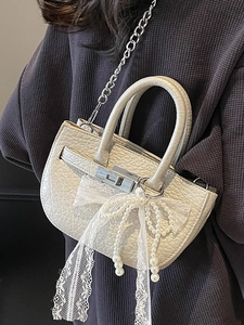 Chic beige textured leather bucket bag with lace bow and pearl chain on a model