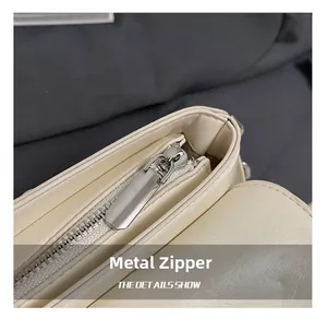 Detail of silver metal zipper and oil wax leather texture on a beige crossbody bag