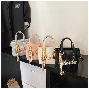 Vue détaillée de mini sacs seaux en quatre couleurs avec broderie de lettres et breloques