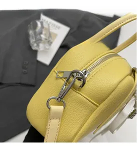 Detail of bright yellow Boston bag featuring silver hardware and lychee grain leather