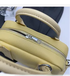 Detail of smooth silver zipper and litchi grain faux leather on yellow Boston bag