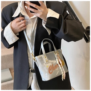 Détail d'un mini sac cabas argenté avec imprimé orange et pendentif en corde tressée chic