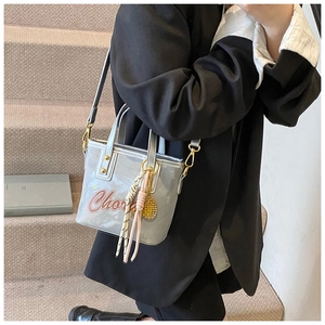 Détail du sac seau gris argenté avec imprimé lettres et texture au fini métallique