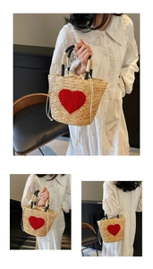 Detail of woven straw tote bag featuring a red plush heart and bicolored handles