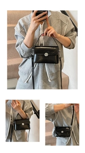Detail showing the black oil wax leather handbag with silver twist lock and crossbody strap