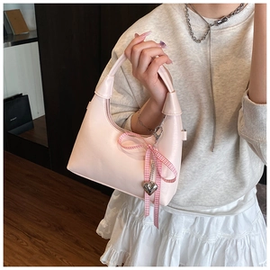 Detail of pink half-moon handbag with checkered bow ribbon and silver heart charm