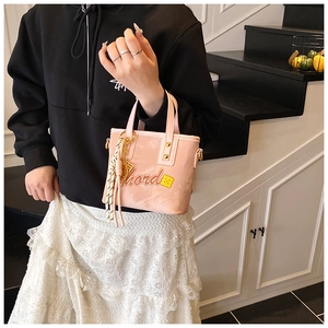 Détail d'un sac seau en cuir verni rose avec motif floral et breloque en cordon noué