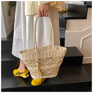 Detail of bohemian hollow-out straw tote bag featuring long wood bead tassels decoration