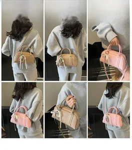 Detail view of mini Boston bags in beige and pink with ribbon and pearl heart charm