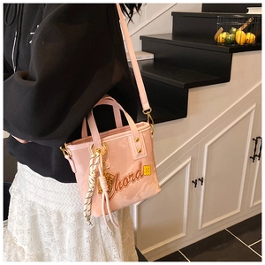 Sac seau rose avec imprimé lettres porté en bandoulière par un mannequin en intérieur