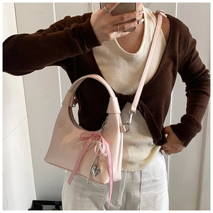 Detail of light pink patent leather handbag with checkered bow and pearl heart charm