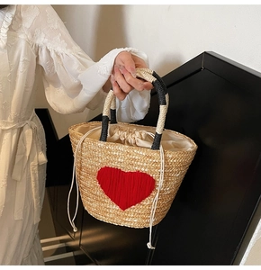 Detailed straw handbag weave with red heart embroidery and drawstring closure