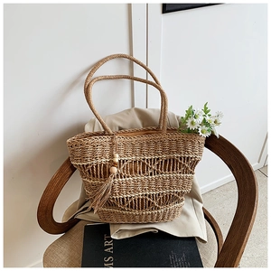 Detailed close-up of bohemian hollow woven straw bag with wood bead tassel decoration