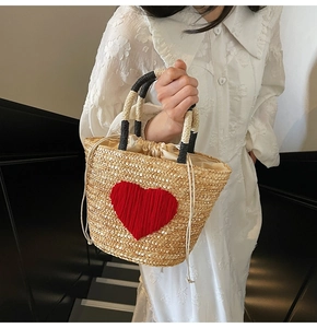 Detail of hand-woven straw bag with red heart pattern and drawstring lining