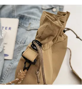 Detail of khaki drawstring bucket bag with durable woven rope and metal hook closure