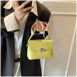 Detail of lime yellow oil wax leather handbag with silver metallic twist lock on flap