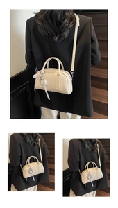 Detail view of cream Boston bag with lychee grain texture and bead ribbon charm