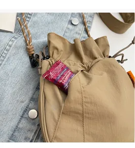 Close-up of utility front pocket on khaki nylon bucket bag with durable drawstring closure