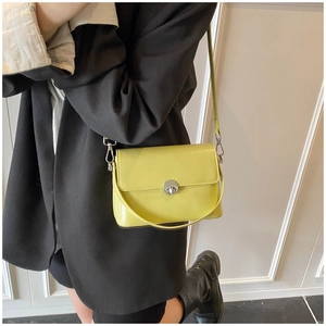 Detail view of bright green glossy leather handbag with silver twist lock on model