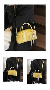 Detailed views of yellow Boston bag with pearl heart pendant on wooden stairs