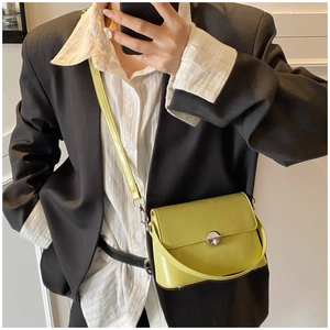 Detail of a bright lime green oil wax leather crossbody bag with a metal twist lock