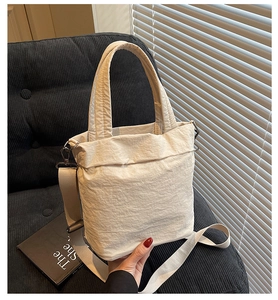 Close-up of cream white tote bag with crinkled texture fabric on a velvet sofa