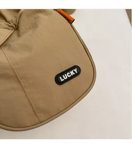 Close-up of khaki nylon bucket bag showing Lucky rubber patch and orange woven brand tag