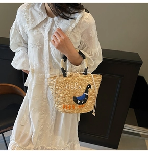 Detail of hand-woven straw bag with Hola embroidery and navy bird motif with drawstring