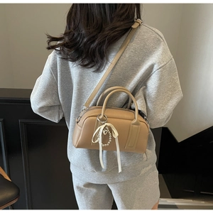 Rear view of khaki Boston bag with ribbon pearl charm on casual grey sweatsuit