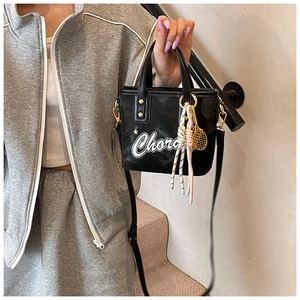 Détail du sac seau en cuir noir avec imprimé Chora blanc et breloque raquette de tennis