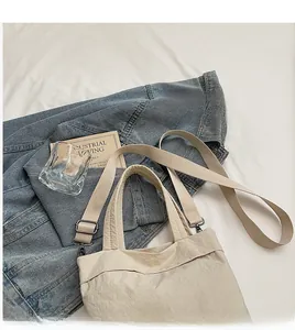Detail view of the adjustable long shoulder strap on a cream white canvas tote bag