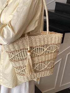 Bohemian style hollow straw woven tote bag for women with tassel detail and large capacity