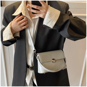 Detail view of light grey wax leather crossbody bag with silver turn-lock and crossbody strap