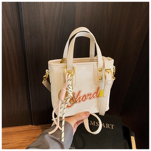Vue détaillée du sac seau blanc avec imprimé lettres orange et charm en corde tissée