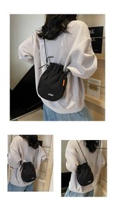 Detail view of the lightweight black drawstring bucket bag with white LUCKY label on back