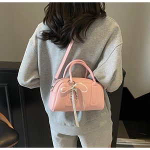 Detail of soft pink Boston bag with lychee leather texture and heart bead charm