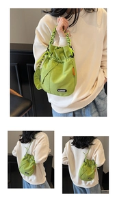 Detail of the green drawstring bucket bag with Lucky patch and braided rope shoulder strap