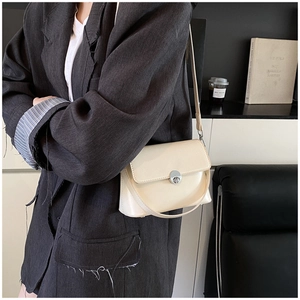 Close-up of a cream oil wax leather crossbody bag with a silver round twist lock detail