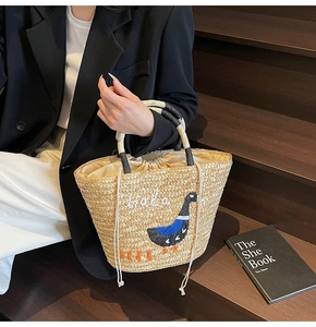 Detail of hand-woven straw bag with colorful bird embroidery and Halo text accents
