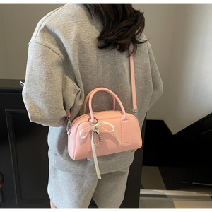 Pink lychee grain Boston bag with heart pendant and ribbon shown on a model