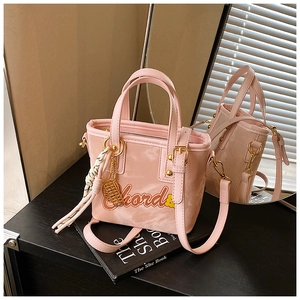 Sac seau rose tendance avec lettrage chord, pompon rayé et garnitures en métal doré