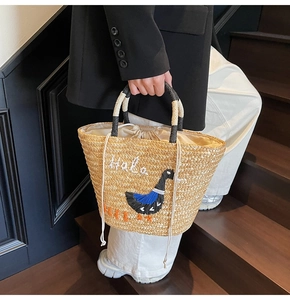 Detailed straw handbag with cartoon embroidery and secure cream drawstring closure