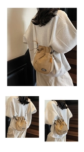 Detail of khaki drawstring bucket bag showing adjustable strap and LUCKY patch logo