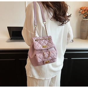 Detail view of a quilted lilac shoulder bag with gold chain and twist lock on a model