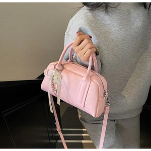 Pink lychee textured Boston bag with pearl charms worn by a model on stairs