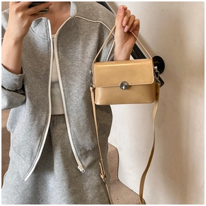 Elegant khaki oil wax leather crossbody bag with silver twist lock on a shoulder strap