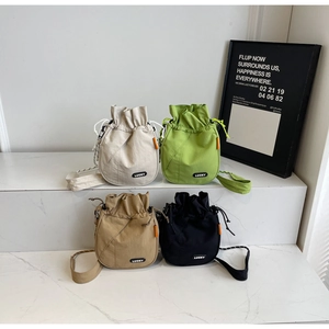 Detail view of lightweight drawstring bucket bags in cream, green, khaki, and black colors