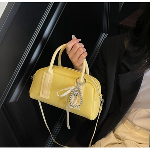 Detail of lemon yellow Boston bag with litchi texture and silver heart charm decoration