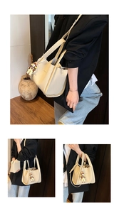 Dettaglio borsa a secchiello beige grana con tracolla e ciondolo a orsetto