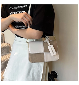 Detail of color-block tote bag featuring khaki and white panels with gold hardware
